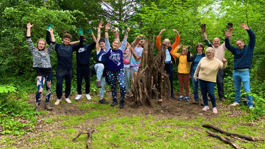 Group of people with arms in the air, in a green space