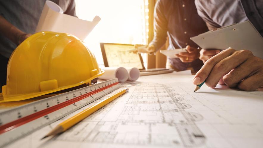 Three colleagues discussing data working and tablet, laptop with on on architectural project at construction site at desk in office